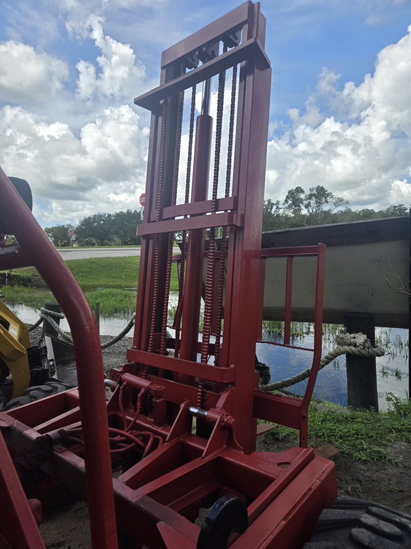 Elevated telescopic lift component showing vertical steel frame with hydraulic cylinders and chain-drive mechanism attached to a red base.