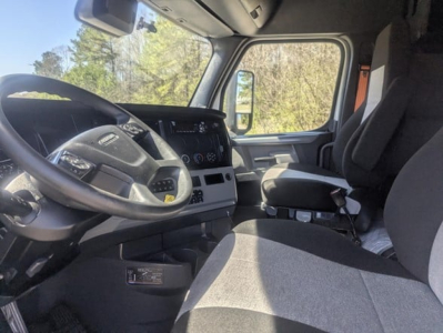 Truck cab interior showing steering wheel, dashboard, and driver's seat in a Freightliner Cascadia 126 sleeper cab.