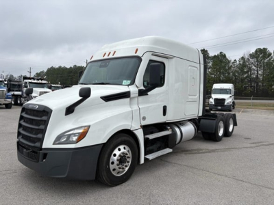 Freightliner Cascadia 126 tractor in a lot, white cab with sleeper, side exhaust, front grille, and dual rear axles.