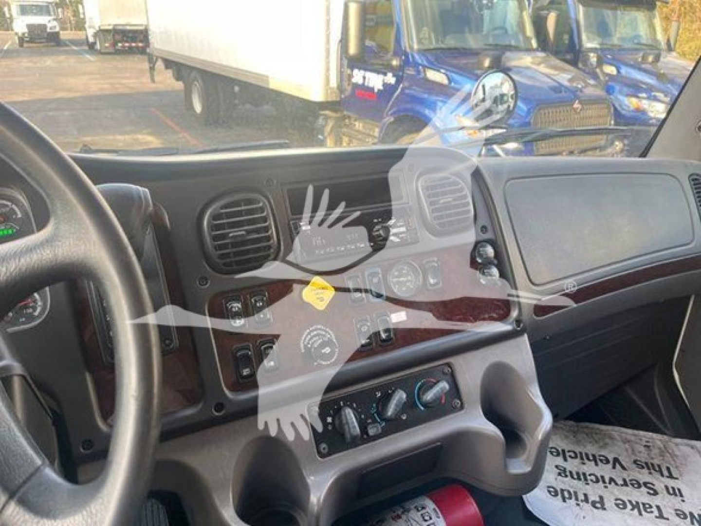 Cab interior of a 2019 Freightliner M2 106 showing dashboard controls and steering wheel with a partial view of the windshield; ambient light through door window.