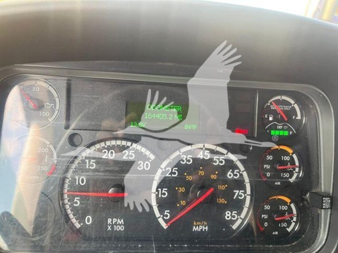 Dashboard cluster showing multiple gauges on a Freightliner M2 106; tachometer, speedometer, and auxiliary gauges with numbers, dials, and digital readouts partially obscured.
