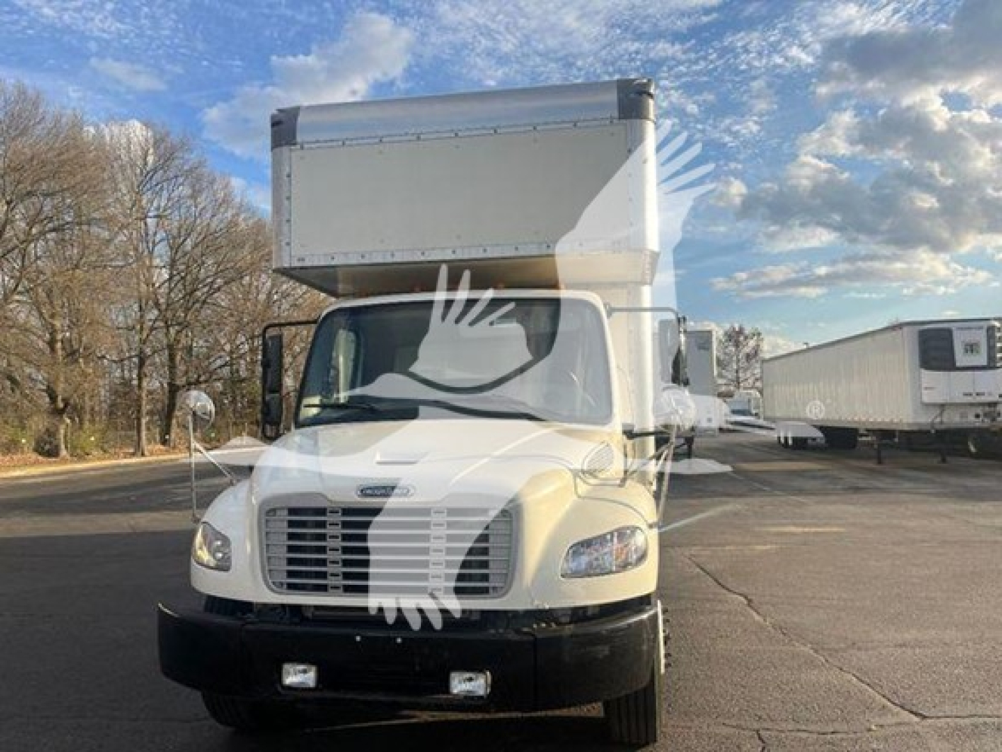 Freightliner M2 106 cab in view with large box on a light-colored truck. Front grille, bumper, headlights visible.