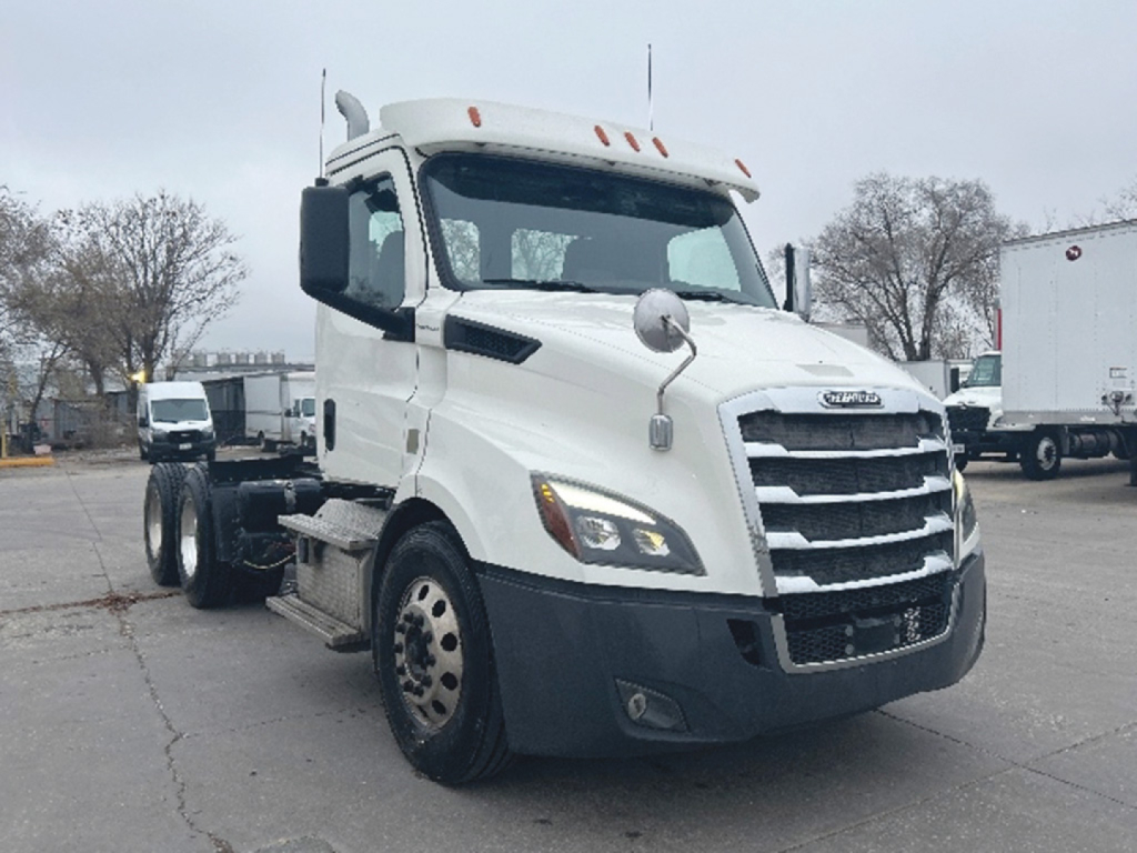 Freightliner Cascadia daycab tractor in white front-left view showing grille, headlights, and side mirror.