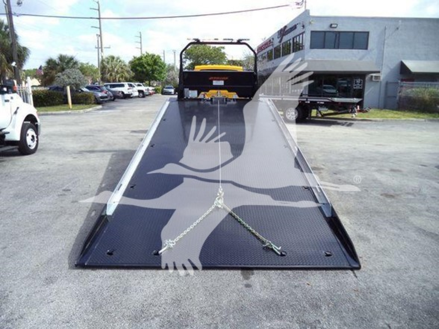 Truck rollback bed on a 2019 International Durastar 4300, low-angle view showing ramp with chains and hooks, VIN 1HTMMMML0KH382488.