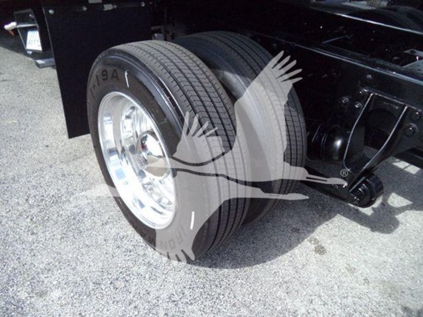 Truck rear dual tires and chassis view showing heavy-duty suspension and steel frame.
