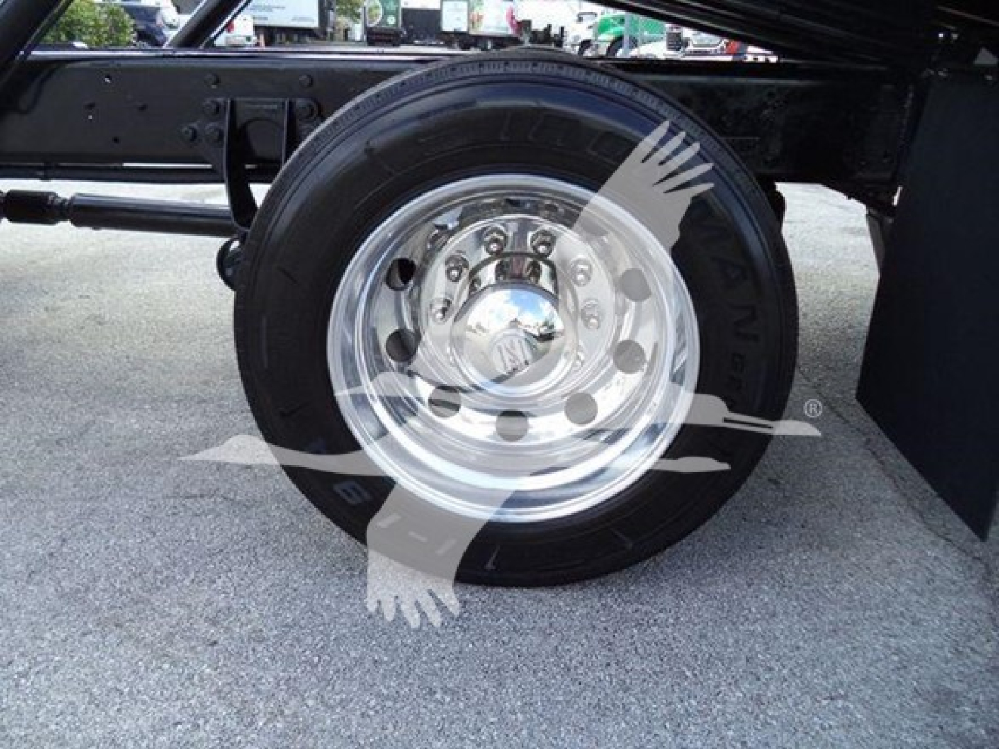 Wheel and tire of a 2019 International Durastar 4300 rollback truck showing chrome steel wheel and black tire, undercarriage components visible.