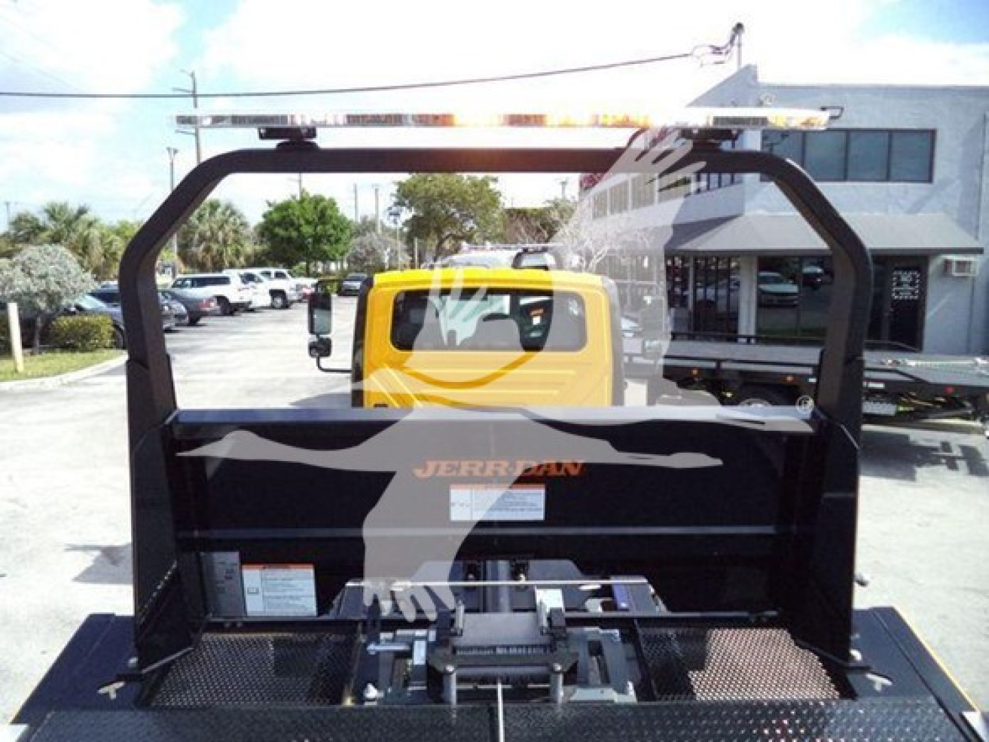 Rear view of a yellow and black Jerr-Dan rollback bed with crane frame, showing platform and control area.