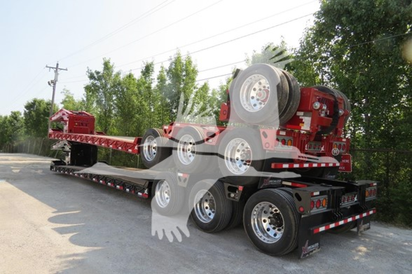 Lowboy trailer with red equipment on flatbed trailer and visible wheels