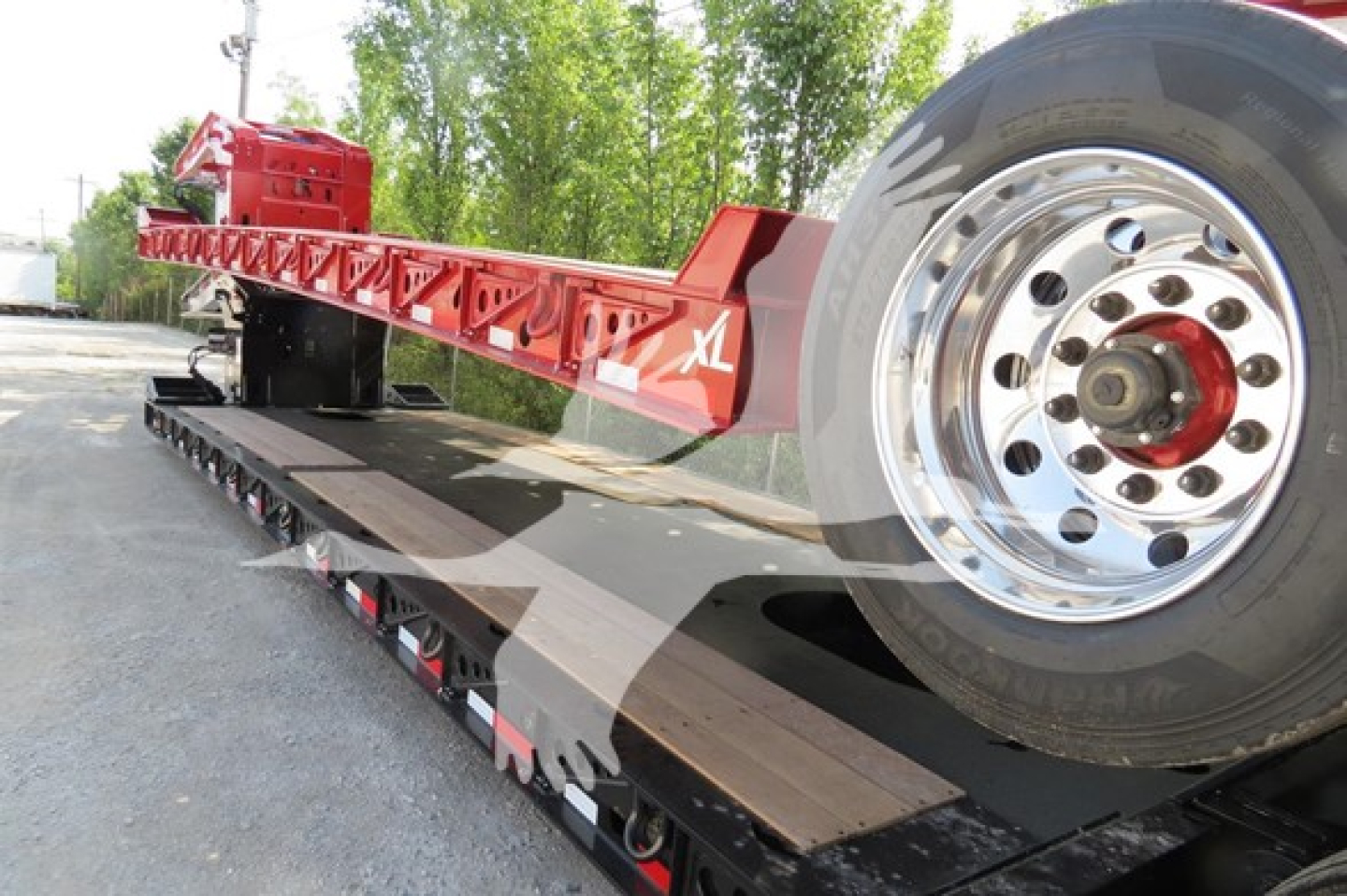 XL Specialized 110Hdg-15 lowboy trailer with red frame and shiny chrome wheel, long flat deck, wheel on the side, heavy-duty construction.