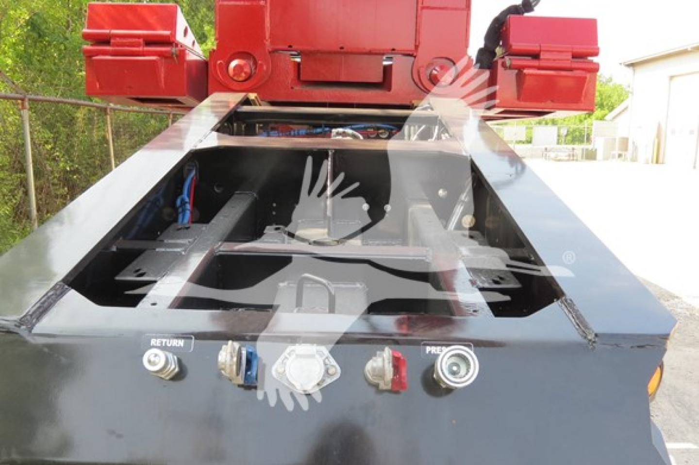 Trailer deck control panel with hydraulic levers and wiring, view from rear of lowboy trailer under carrier crane.