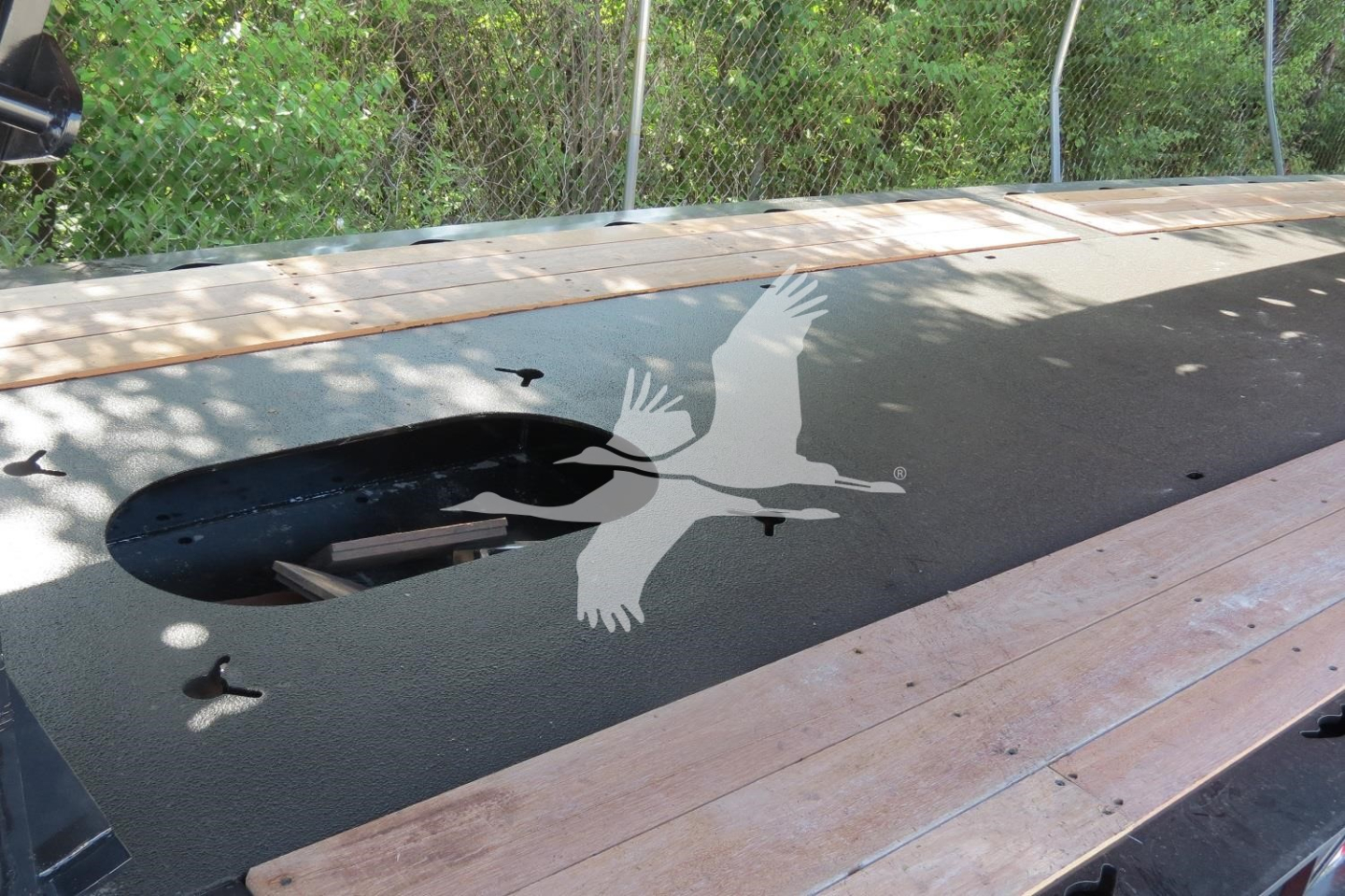 Flatbed trailer deck with a circular cutout and a large flock of seagull graphic on a dark surface.