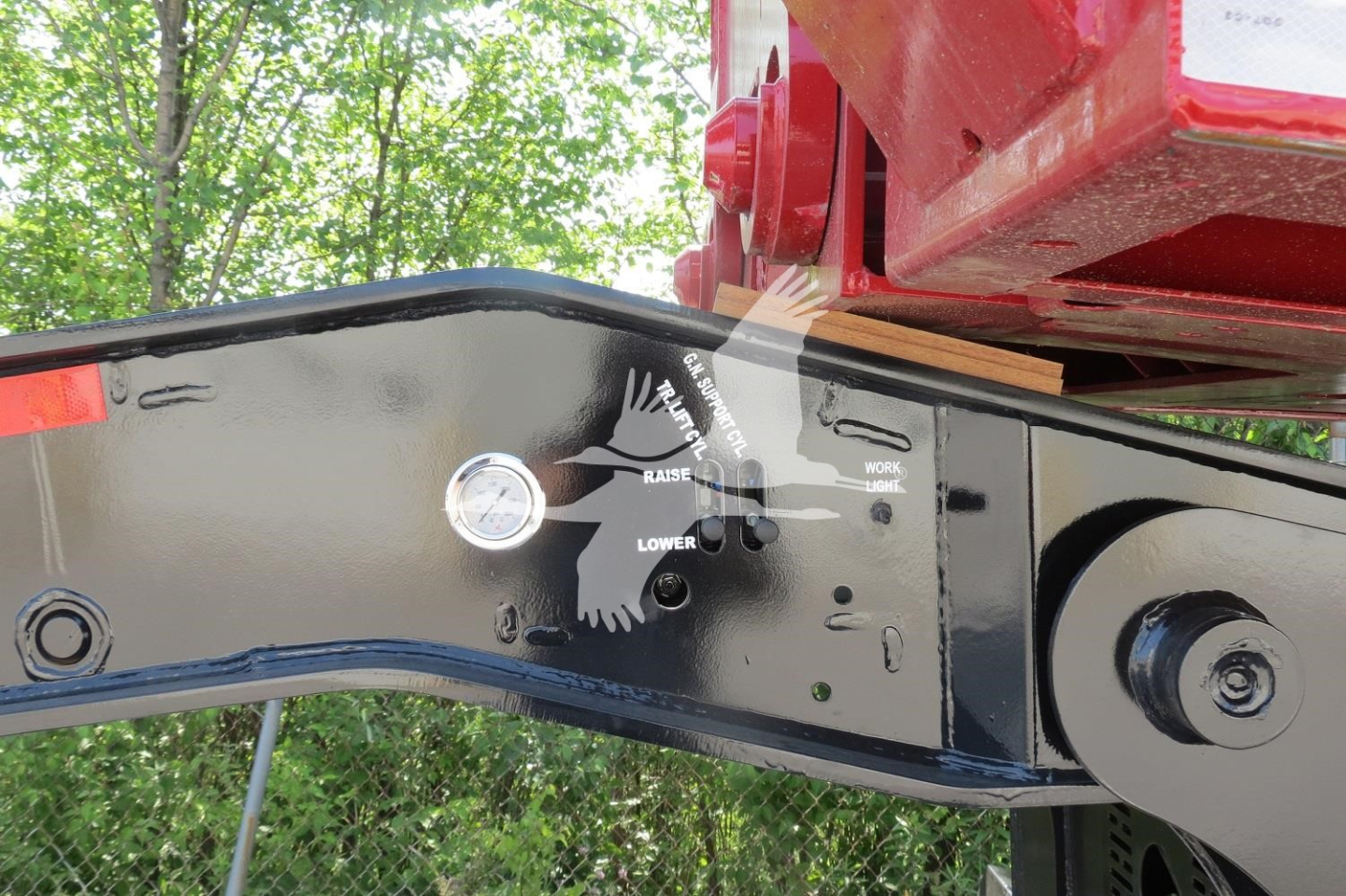 Trailer hitch area with adjustment gauge and labels on black metal frame of XL Specialized 110Hdg-15 lowboy trailer showing markers for upper, lower, and load position.