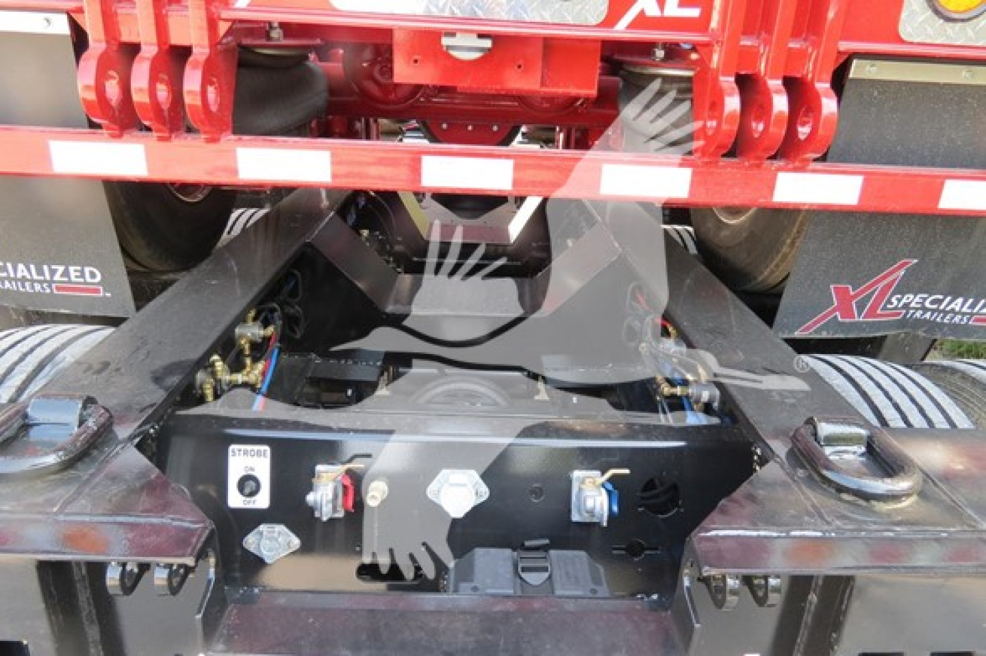 Trailer hitch area of a XL Specialized 110Hdg-15 lowboy trailer showing hydraulic controls and mounting hardware with safety latches.