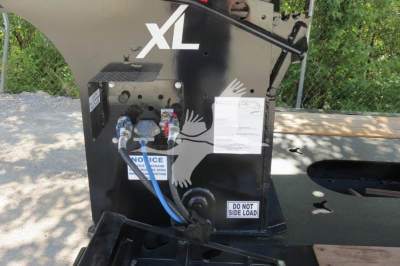 Trailer component with XL branding showing hydraulic connections and a white label, in-service condition on a lowboy trailer.