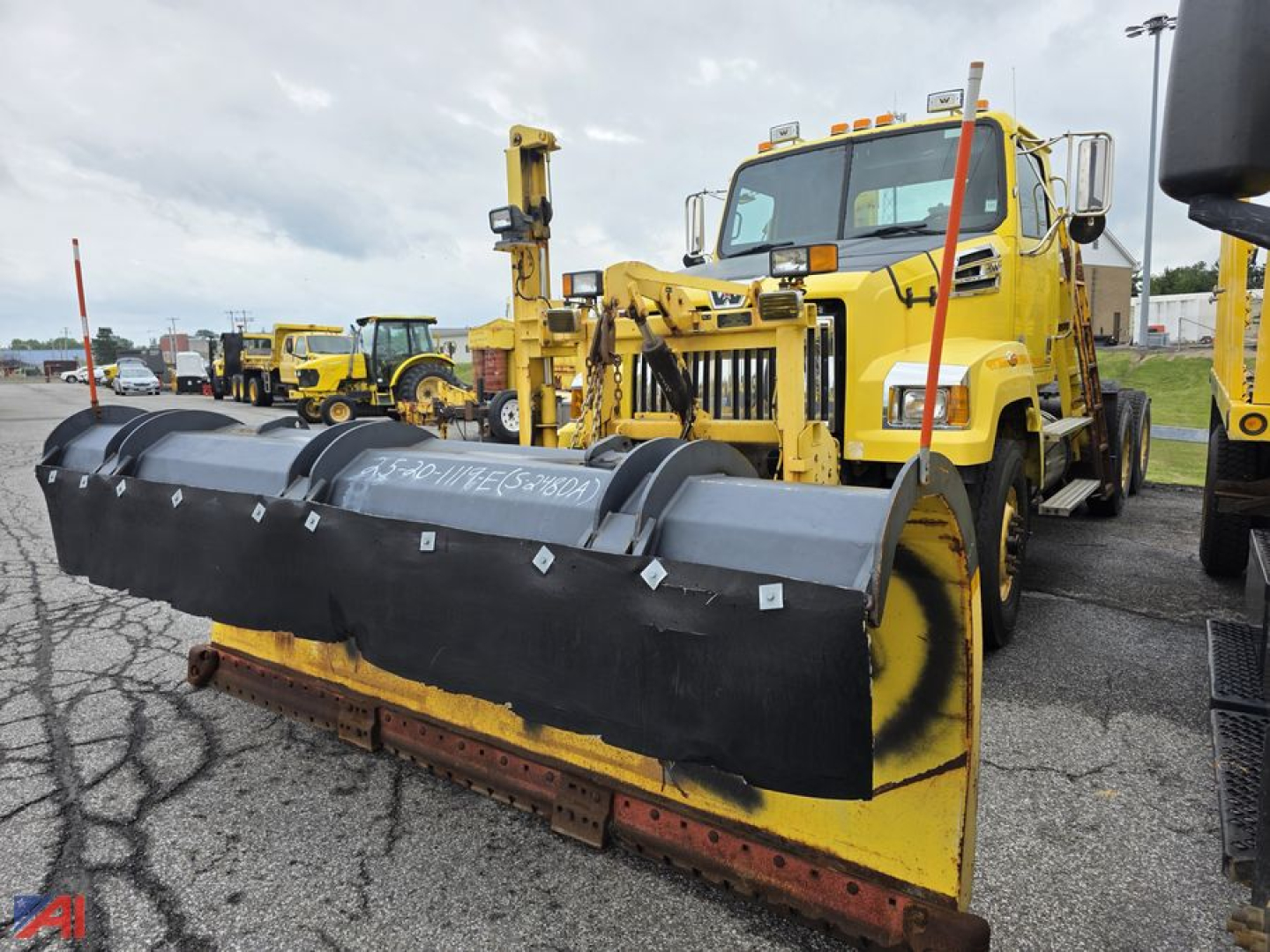 Front mount plow attached to yellow Western Star cab and chassis. Visible markings on plow and vehicle including warning mirrors and warning lights.