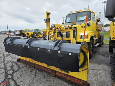 Front mount plow attached to yellow Western Star cab and chassis. Visible markings on plow and vehicle including warning mirrors and warning lights.