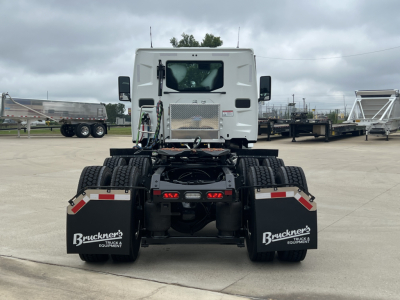 Rear view of a white Mack AN64T daycab truck chassis showing dual rear axles, black mud flaps with 'Bruckner's' branding, and license-plate area; no engine details visible.