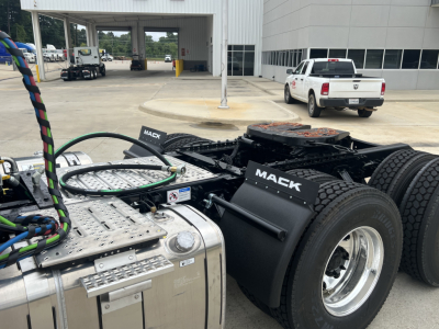 Mack AN64T tractor cab chassis showing fuel tanks and twin rear axles with Mack branding on fenders and exposed hydraulic lines.