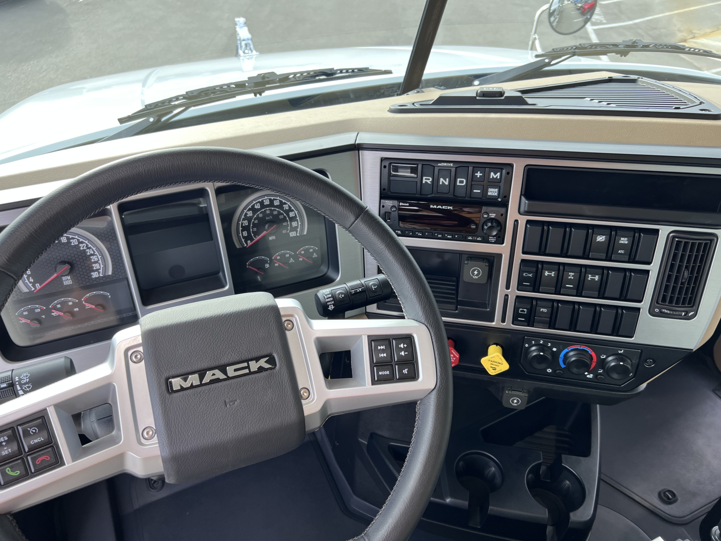 Mack GR64F truck cab interior showing steering wheel and dashboard with gauges and controls.