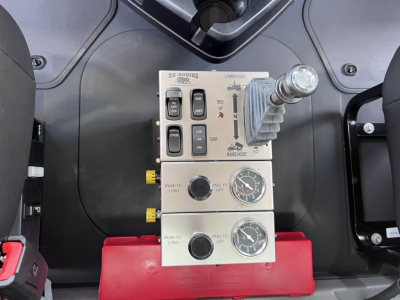 Group of control levers and gauges in Mack GR64F dump truck cab interior panel showing hydraulic controls, switches, and indicators.