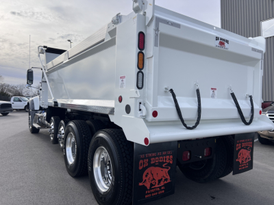 Rear view of a new 2026 Mack GR64F dump truck showing dual rear axles, white dump body, tailgate with lanyard hooks, and rectangular taillights.