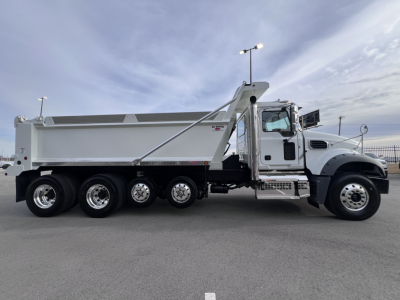 Dump truck side view showing Mack GR64F dump body with 6-wheel tandem rear, chrome wheels, and cab-mounted steps. No visible logos or text legible beyond truck design.