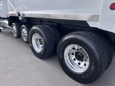 Dump truck wheels and axles showing multiple tires and chrome rims under a Mack GR64F dump body.