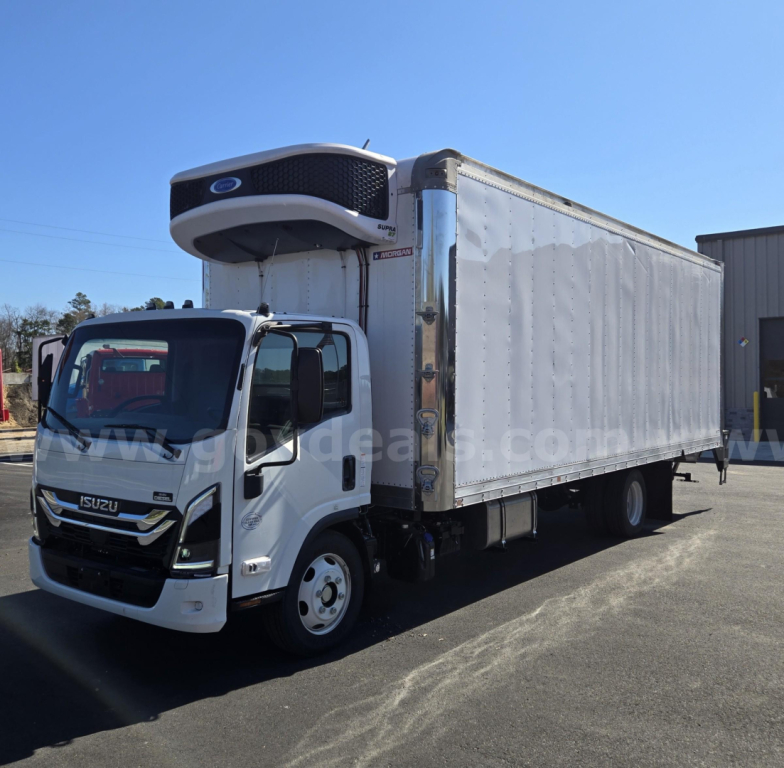 Isuzu NPR box truck with refrigeration unit on the cab, white cab and silver curtain-side box, side view in a lot.