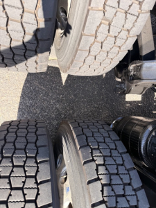 Truck dual rear tires and undercarriage view showing tandem axle setup and mounting hardware.