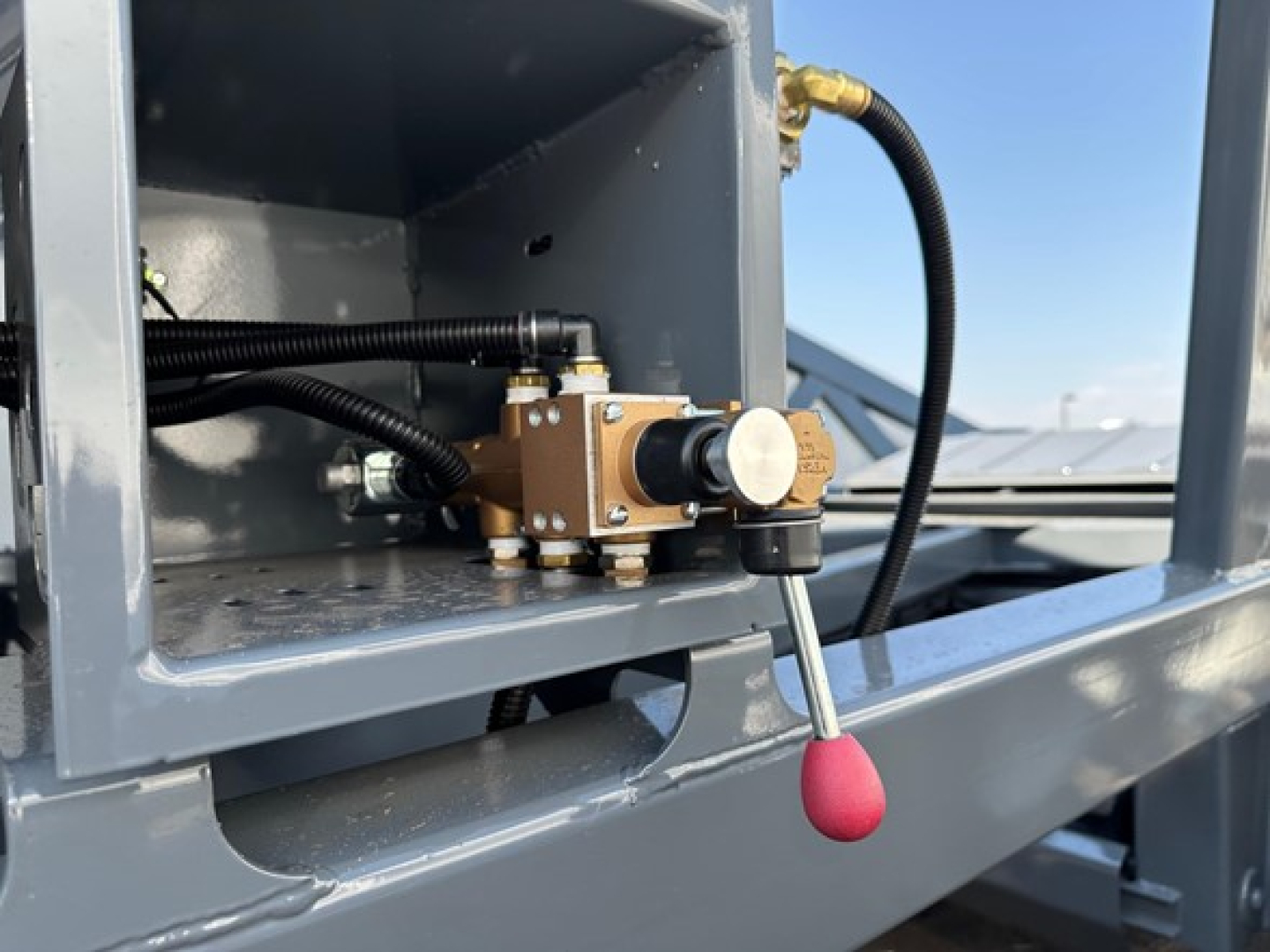 Lw21-40 hydraulic valve assembly mounted in a dump trailer with black hoses and a red-tipped lever.