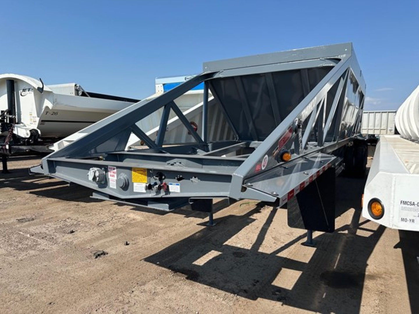 Ranco LW21-40 dump trailer in a yard showing open-weave truss frame with gray paint and reflective tape on sides.