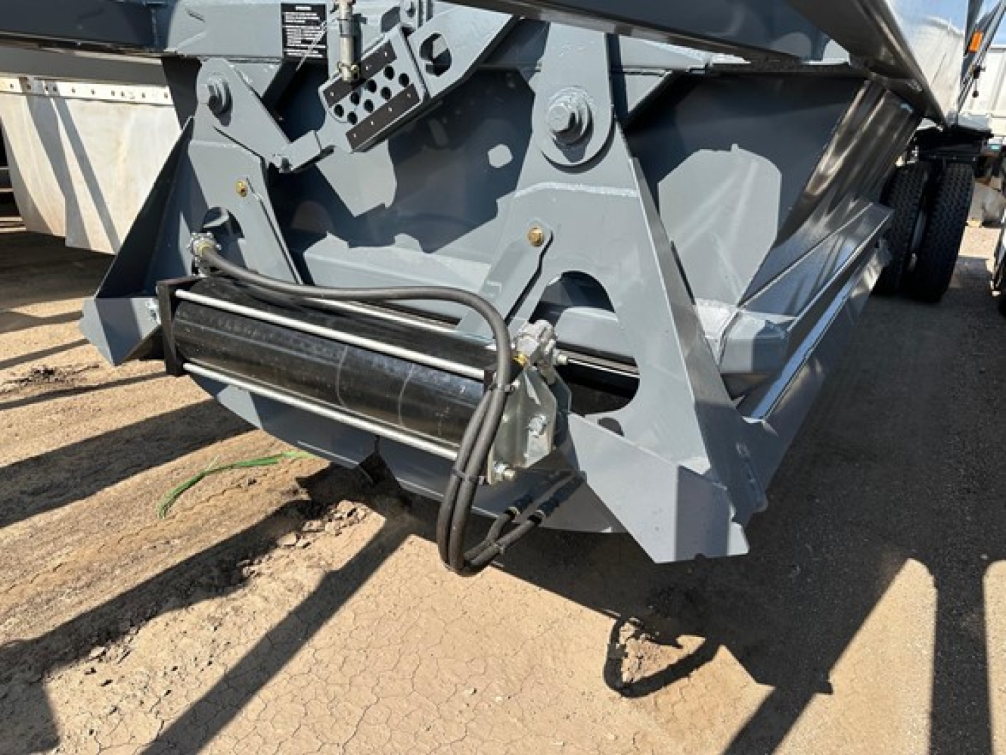 Ranco LW21-40 component showing hydraulic hose, roller guide, and metal frame on dump trailer hitch area.