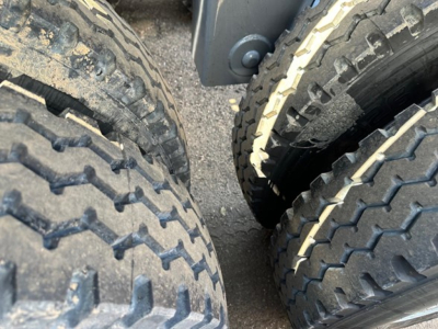 Wheel tires of a dump trailer showing dual rear tires with tread patterns and mud on the sidewalls.