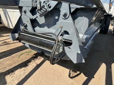 Ranco LW21-40 component showing hydraulic hose, roller guide, and metal frame on dump trailer hitch area.