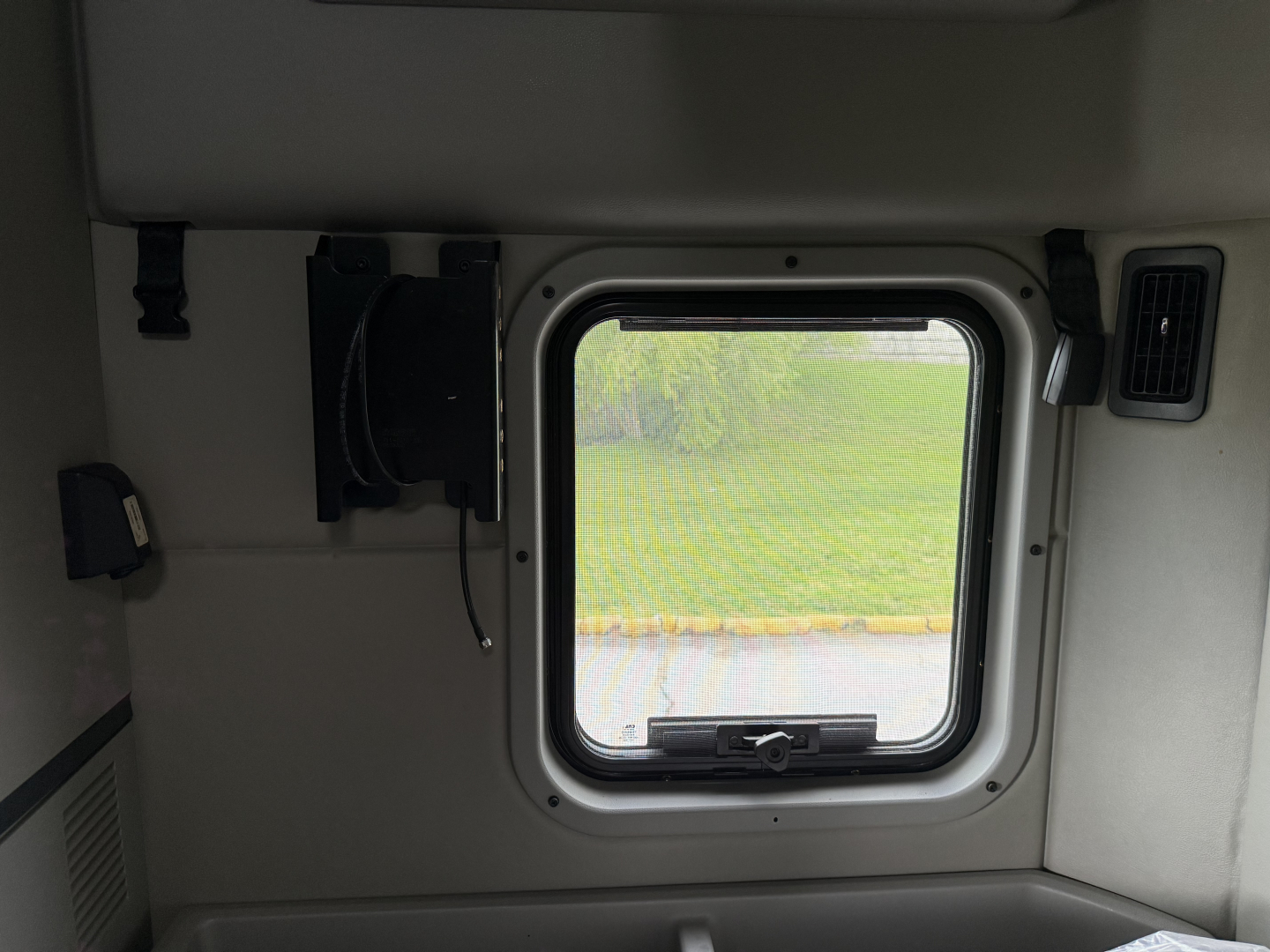 Peterbilt 579 truck cab interior window view and small equipment mounted on wall.