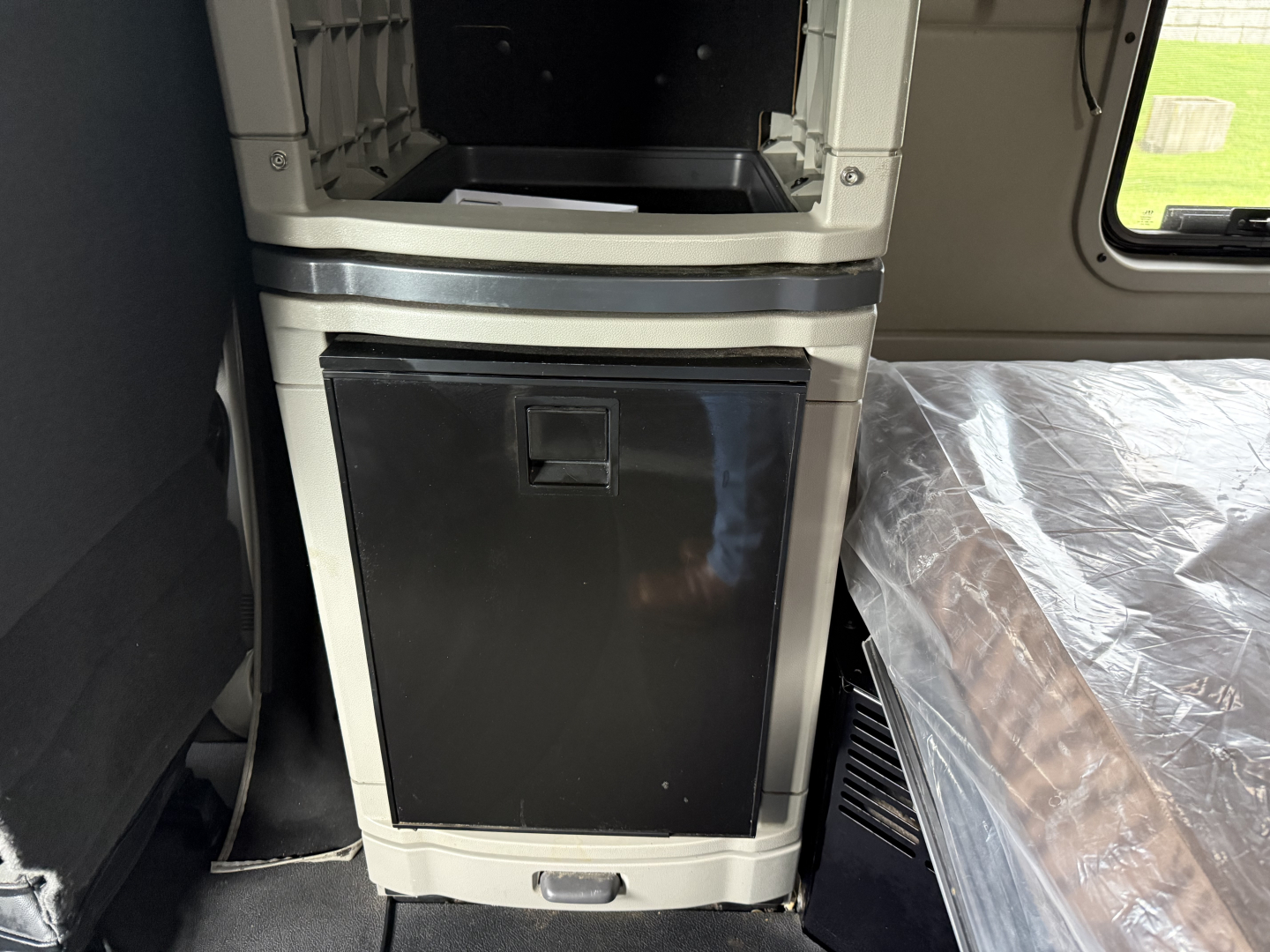 Panel and cabinet area inside a Peterbilt 579 cab showing a black vertical storage cabinet door and surrounding light gray panels with a silver trim.