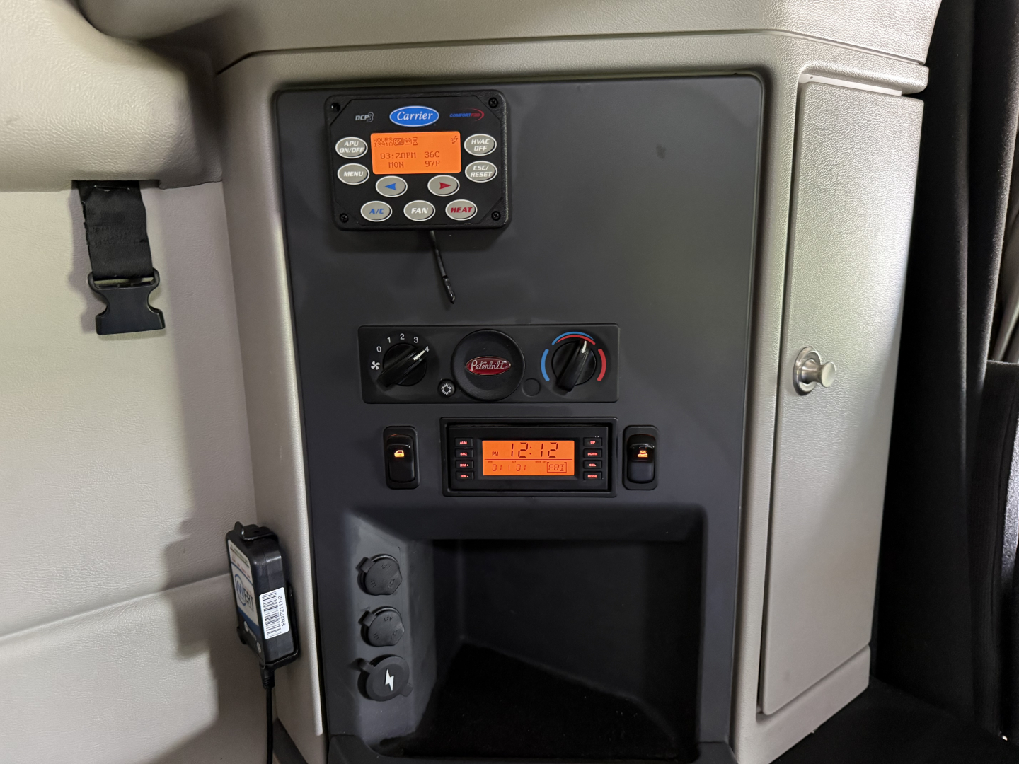 Peterbilt 579 dash area showing CB radio control panel, climate controls, and digital display; center console with knobs and storage compartment.