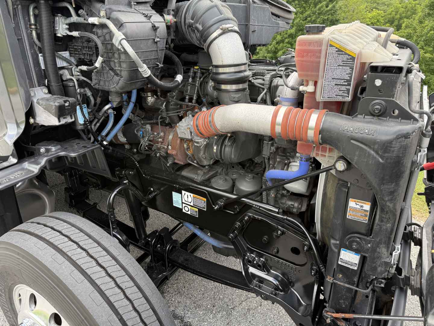 Peterbilt 579 engine bay showing intake hoses, coolant reservoir, and engine components visible in front of the cab.