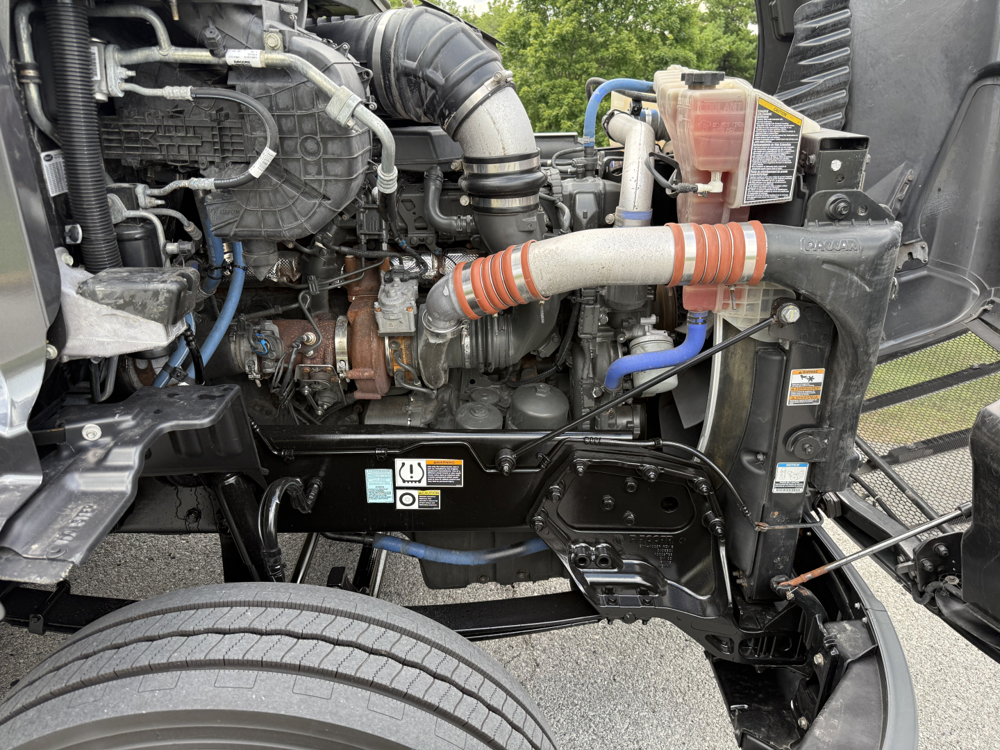 Peterbilt 579 engine bay close-up showing intake hoses, coolant reservoir, and engine components.