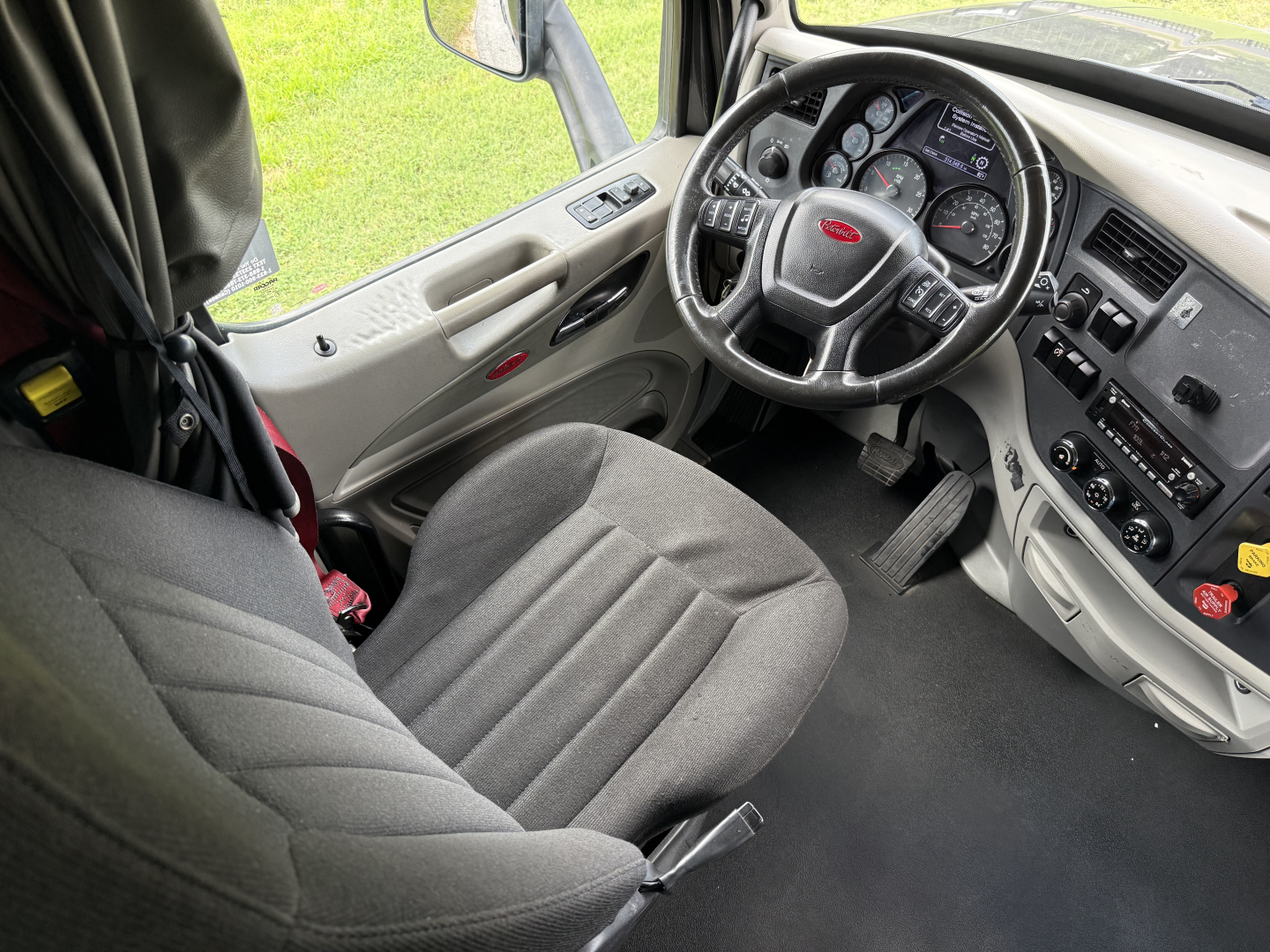 Peterbilt 579 truck interior showing steering wheel, dashboard gauges, driver seat, and center console.