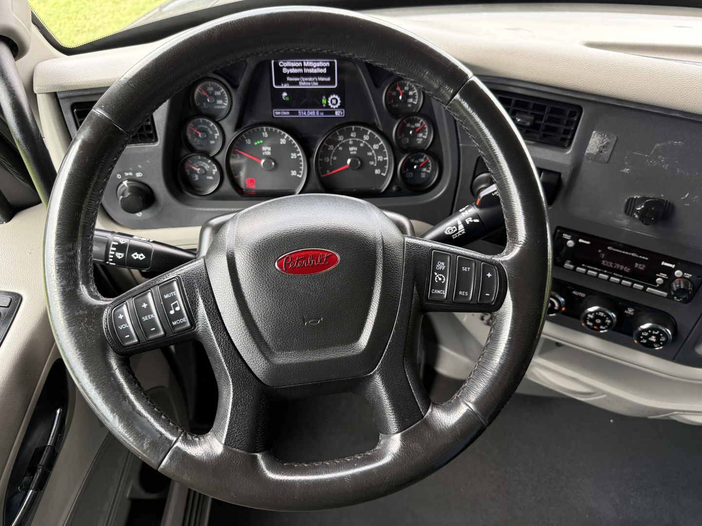 Peterbilt 579 steering wheel and dashboard with gauges and center screen, interior view from driver seat.