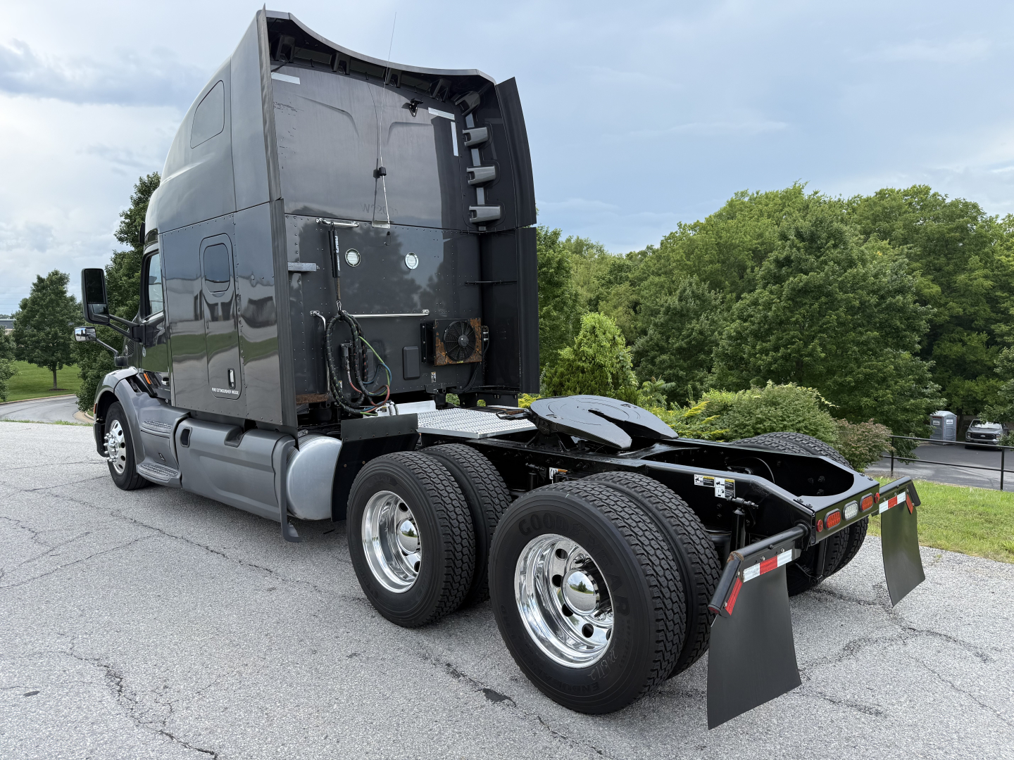 Peterbilt 579 tractor rear view showing fifth wheel, dual rear axles, and mud flaps in a truck yard.