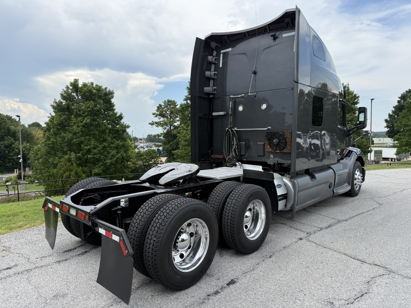 Peterbilt 579 tractor rear view showing fifth wheel and dual rear axles with chrome wheels and black sleeper cab.