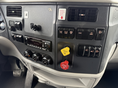 Peterbilt 579 dash panel with switches, knobs, and two colored knobs (yellow and red) in view; includes radio and climate controls.