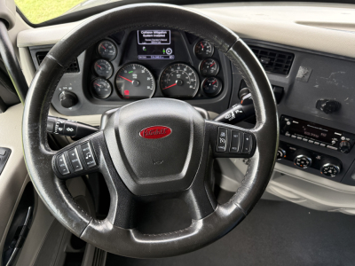Peterbilt 579 steering wheel and dashboard with gauges and center screen, interior view from driver seat.