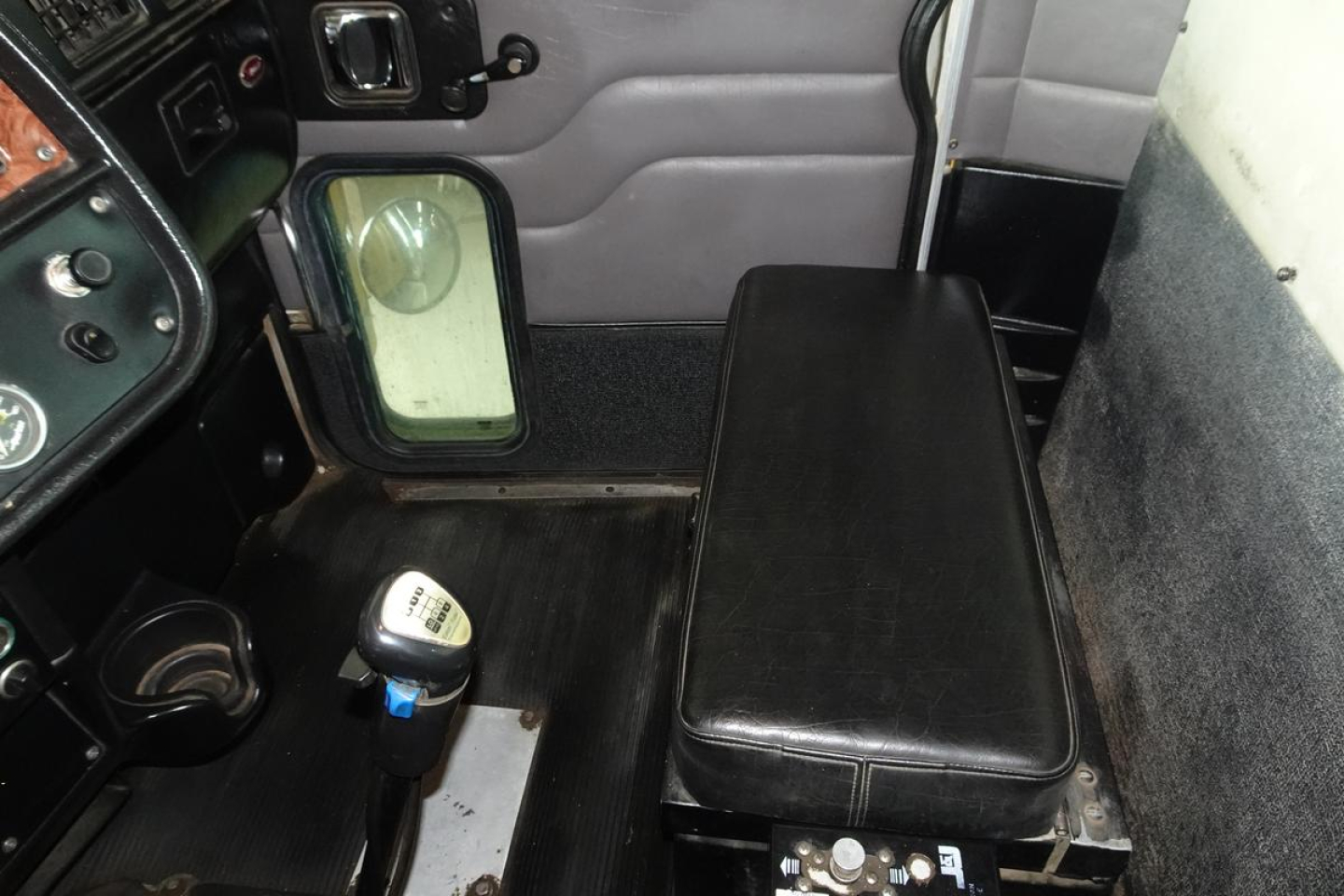 Interior cab area of a 2005 Peterbilt 357 dump truck showing bench seat, gear selector, door panel, and window. Visible text includes 'Peterbilt' on dash label and various switches.