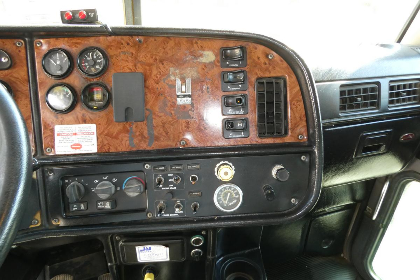 Peterbilt 357 instrument cluster and dashboard with woodgrain panel and assorted gauges and switches.