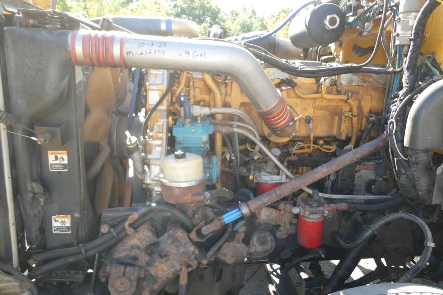 Peterbilt 357 engine bay showing intake tube, radiator, and diesel engine components with hoses and fuel lines.