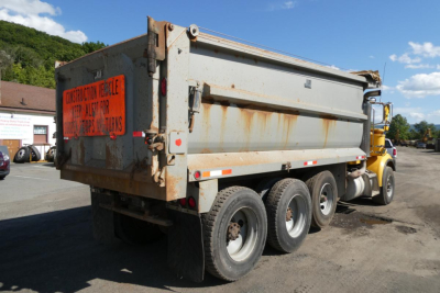 Peterbilt 357 dump truck rear and side showing orange construction vehicle warning label and rusted dump body.