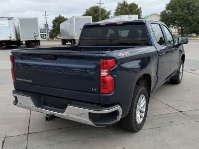 Chevrolet Silverado 1500 LT Crew Cab 4x4 rear view showing bed, taillights, and bumper in dark blue with chrome accents.